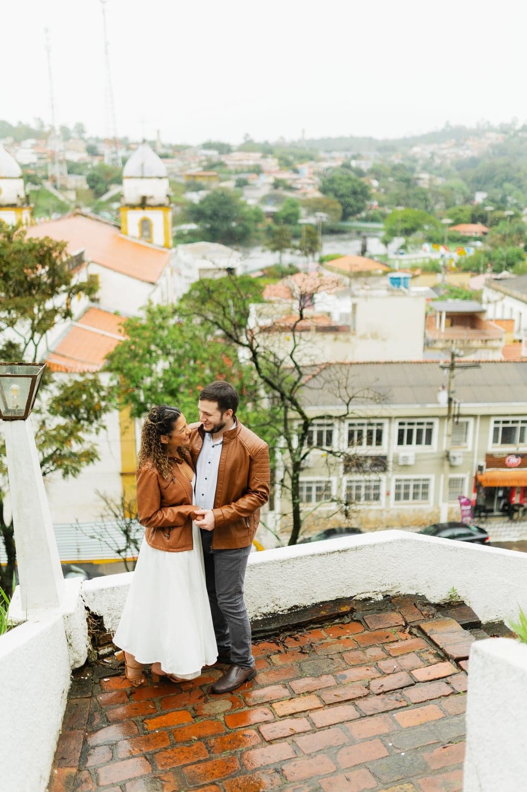 O casal se beijando em frente a um prédio histórico de tijolos aparentes
