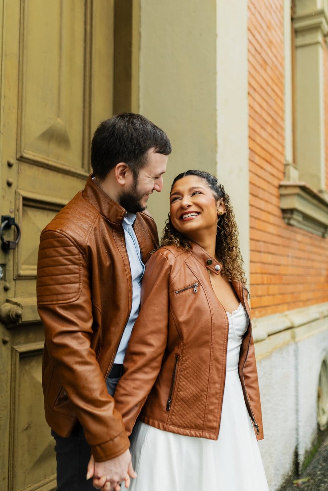 O casal sorrindo e se olhando, Pedro de jaqueta de couro