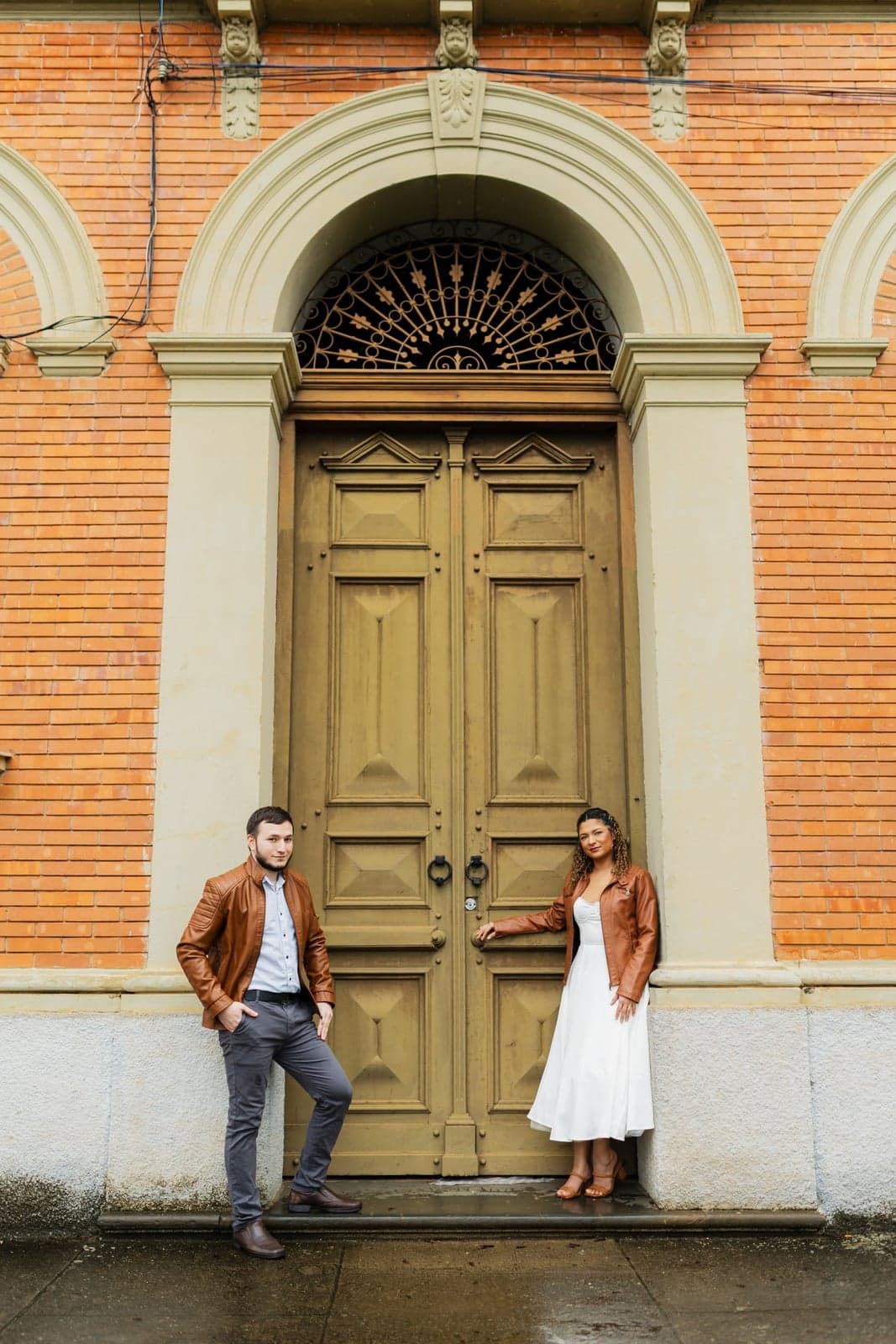 O casal em frente a uma porta antiga de madeira do prédio histórico