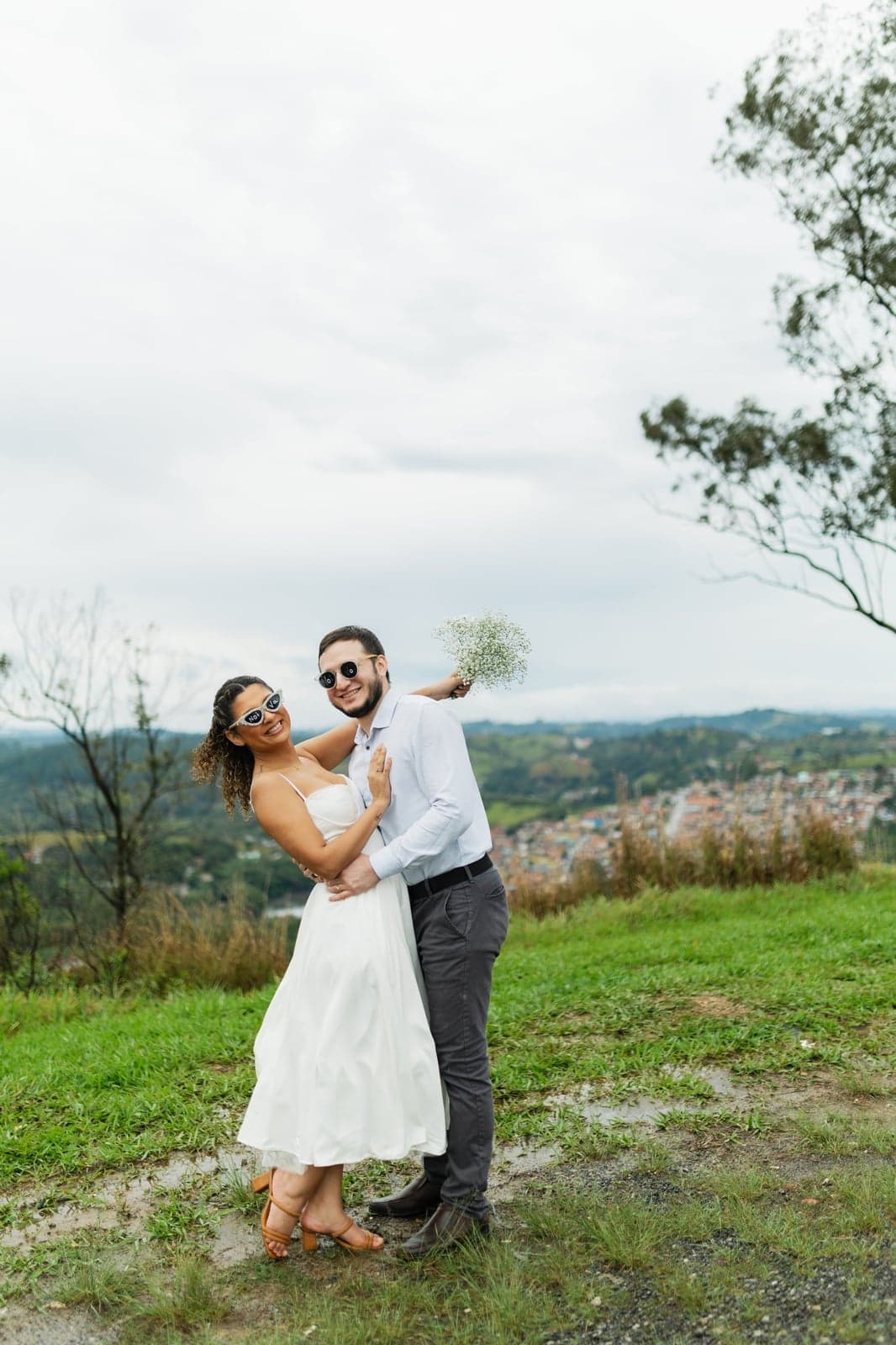 Jessyana sorrindo enquanto Pedro a abraça por trás, no alto do mirante